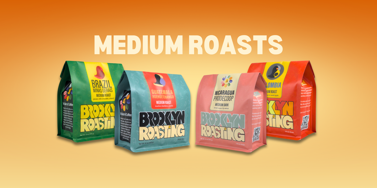 Four Brooklyn Roasting Company medium roast coffee bags side by side: green Brazil, teal Guatemala, pink Nicaragua, and red Colombia, under a "Medium Roasts" text overlay